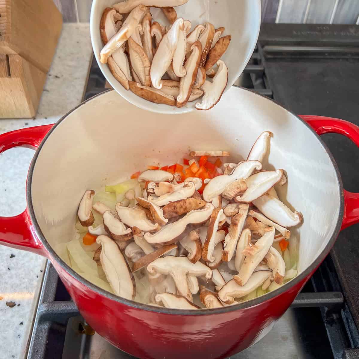 Sliced mushrooms being added to the pot.