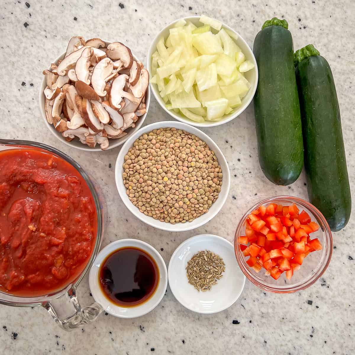 Ingredients for lentil bolognese: green/brown lentils, mushrooms, onion, zucchini, red bell pepper, marinara sauce, fennel seed, balsamic vinegar.