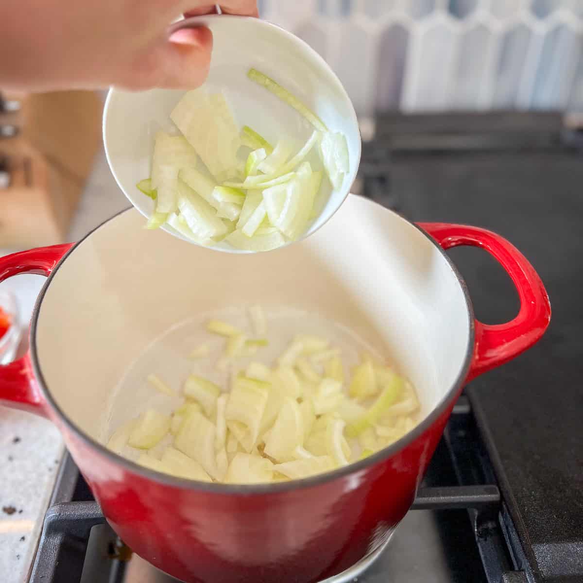 Onions being added to the pot on the stovetop.