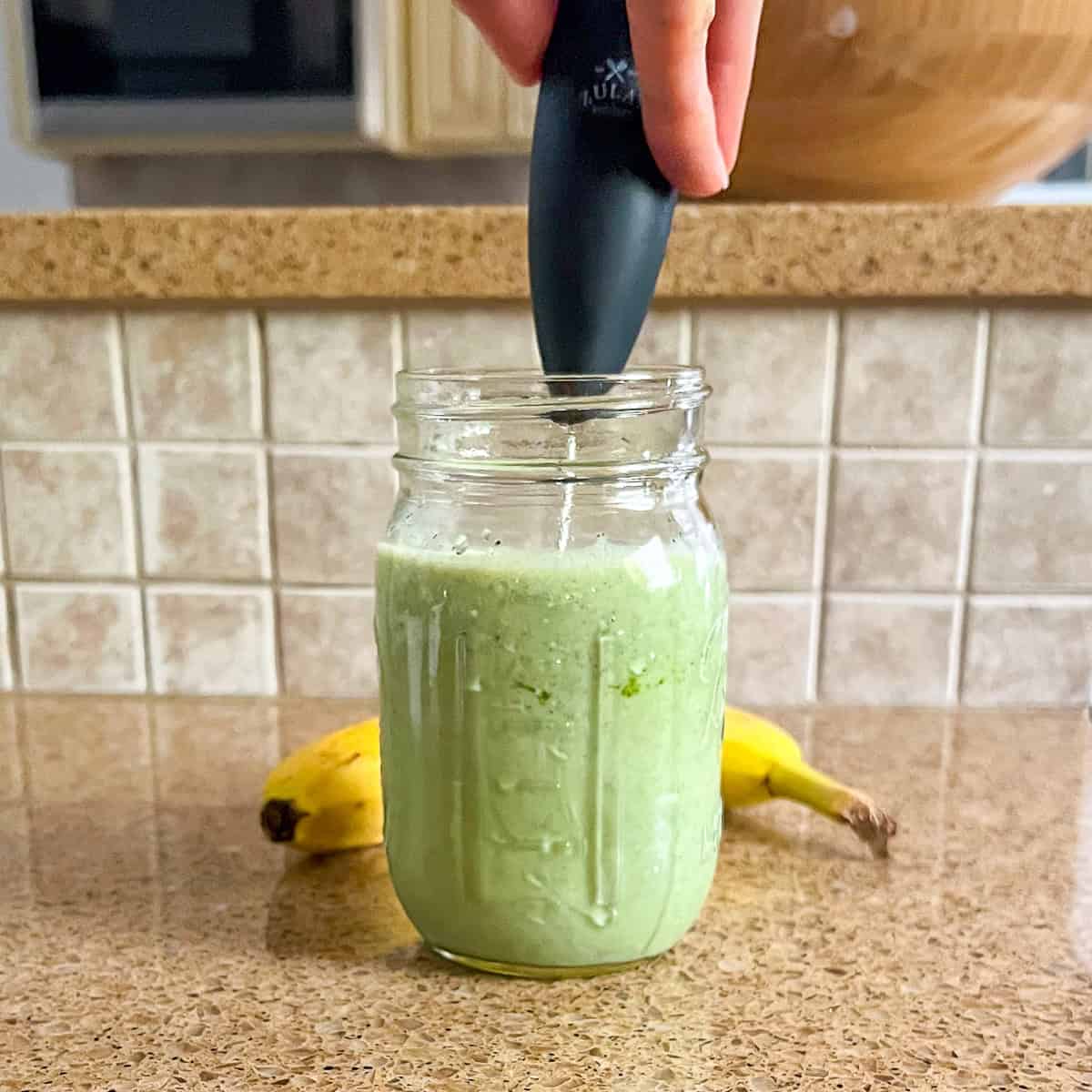 Matcha powder being combined with plant-based milk using a frother.