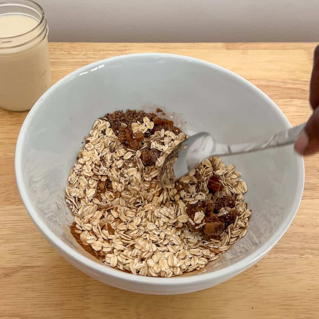Oats mixture in a bowl with spoon stirring.