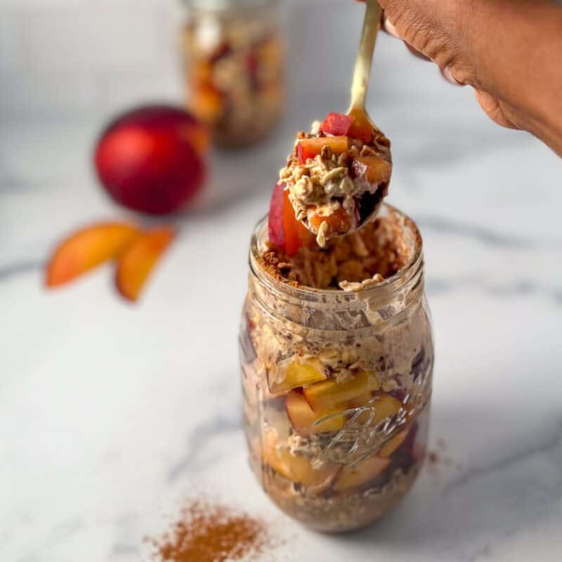 Peach overnight oats in a mason jar with spoon lifting some out.