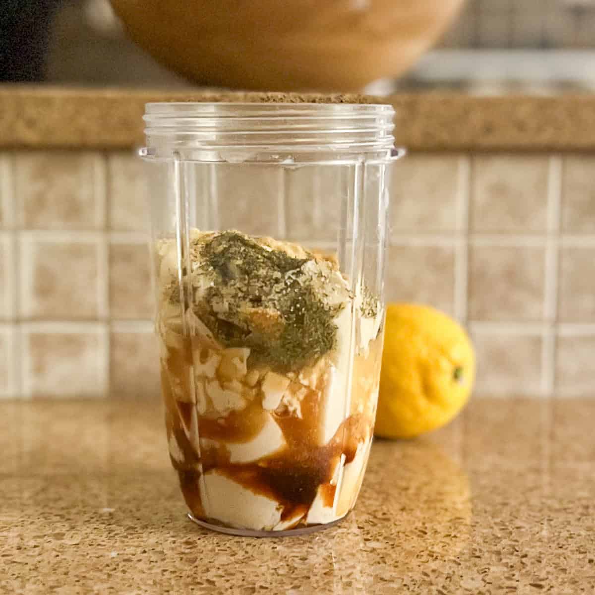 Silken tofu, coconut aminos and other ingredients in a mini blender container.