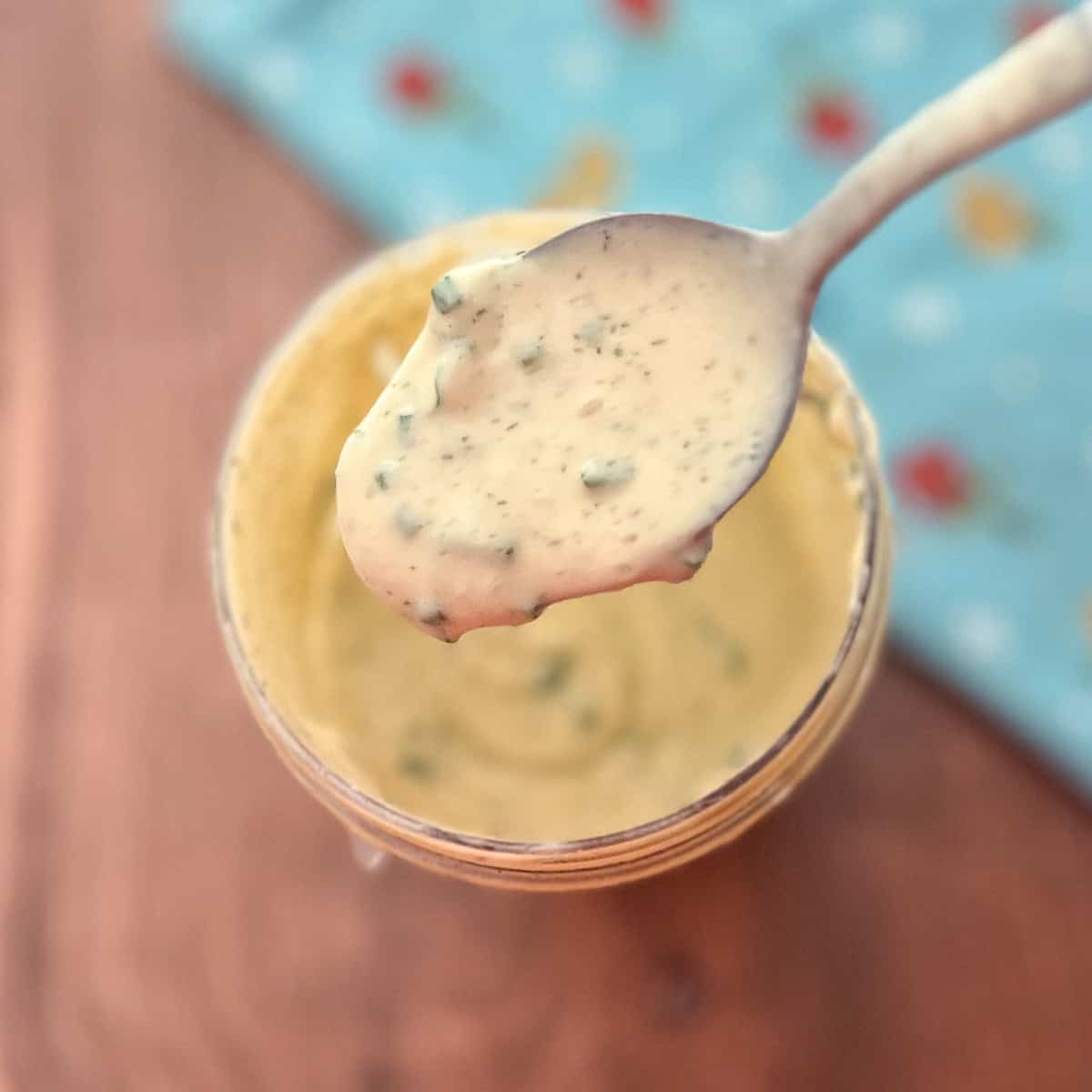 A spoonful of vegan ranch dressing with fresh herbs.