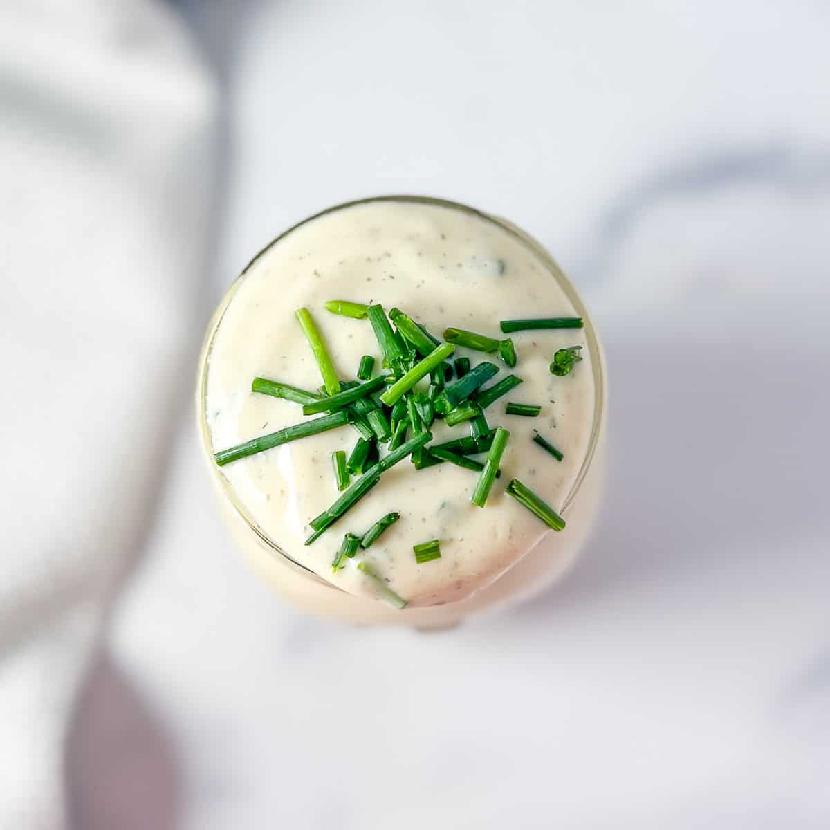 Vegan ranch dressing in a mason jar with chopped chives on top.