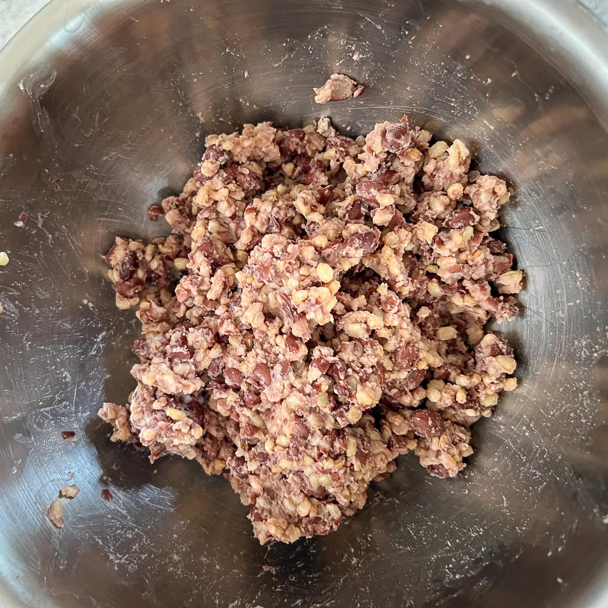 Mashed up black bean and brown rice mixture in a mixing bowl.