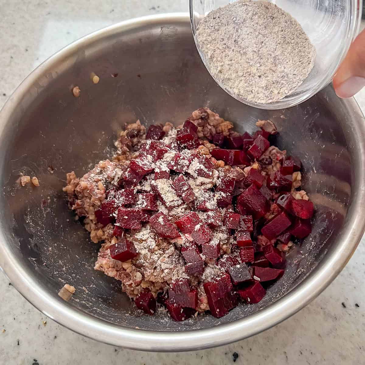 Dried seasonings being sprinkled over the black bean burger mixture.