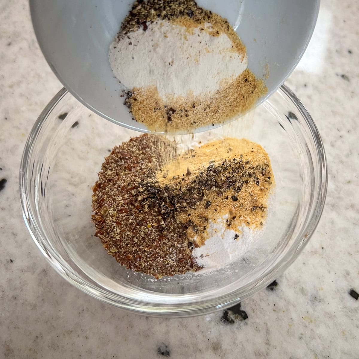 Dried seasonings being added to a small bowl.