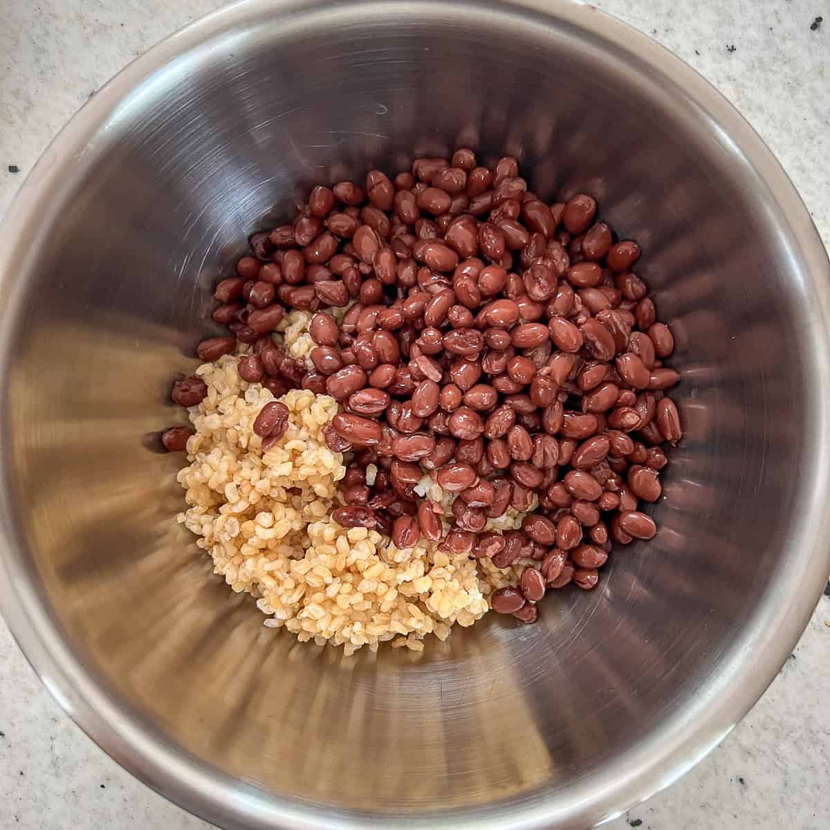 A mixing bowl with cooked short grain brown rice and black beans.