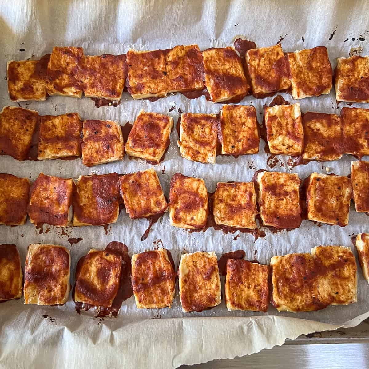 BBQ baked tofu on a parchment-lined baking sheet.