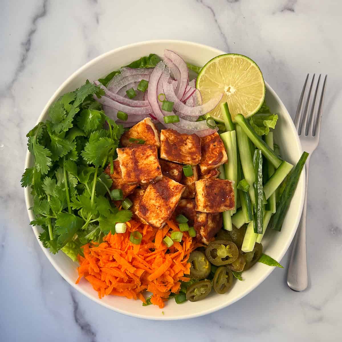 Banh mi salad in a bowl topped with BBQ tofu, fresh veggies and herbs.