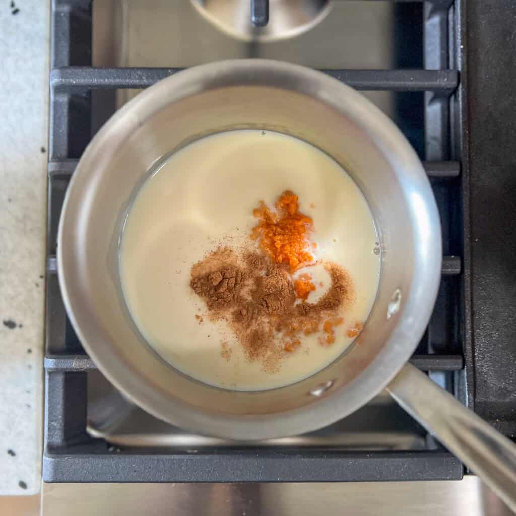 Soy milk, pumpkin puree, pumpkin pie spice and maple syrup in a small pot on the stovetop.