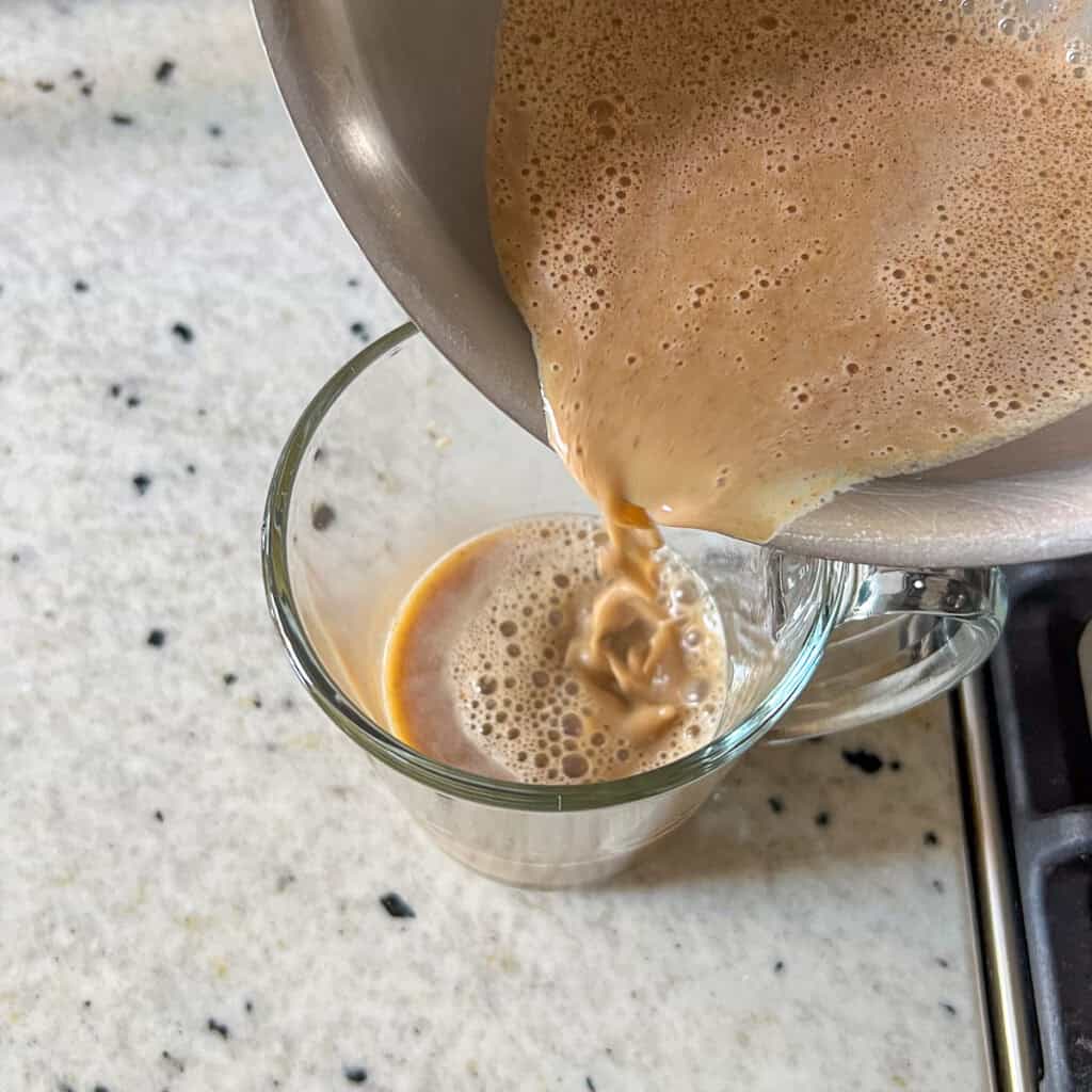 Pumpkin latte mixture being added to the chai tea in the mug.