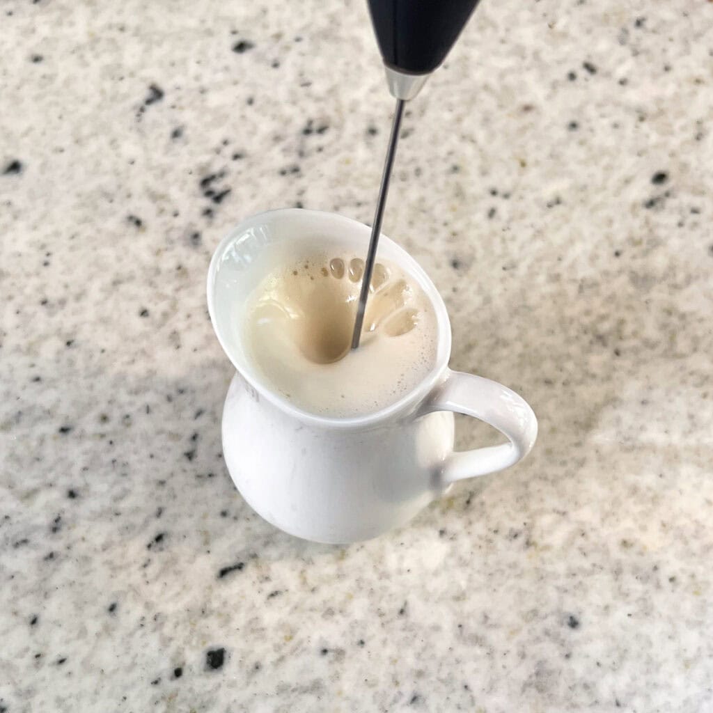 Soy milk being frothed with a frothing wand.