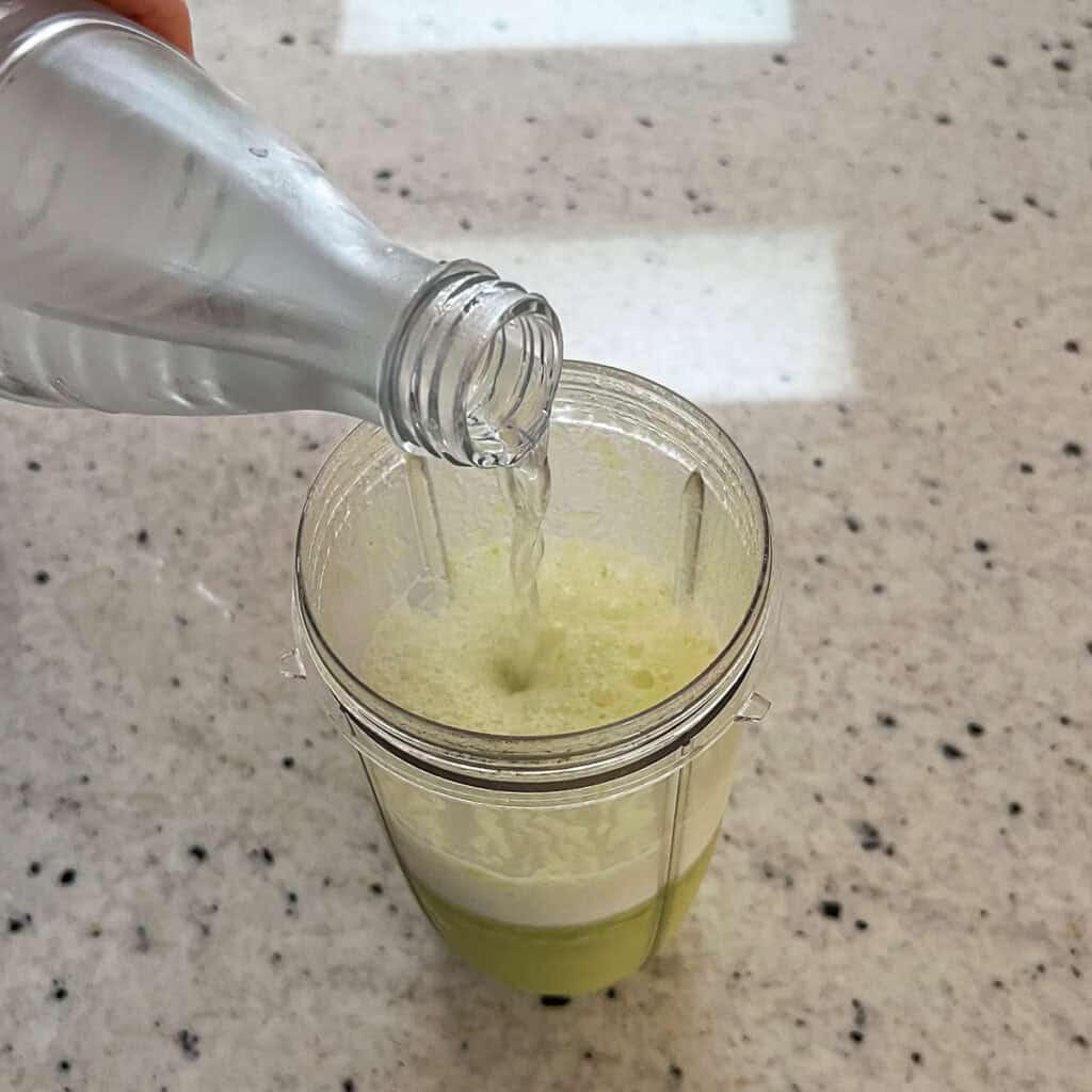Sparkling water being poured into the blender cup.