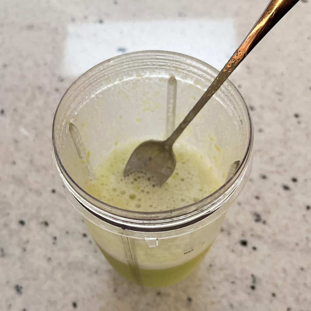 The mocktail being stirred with a spoon.