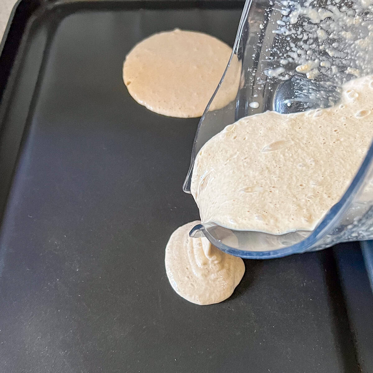 Pancake batter being poured onto a heated nonstick griddle.