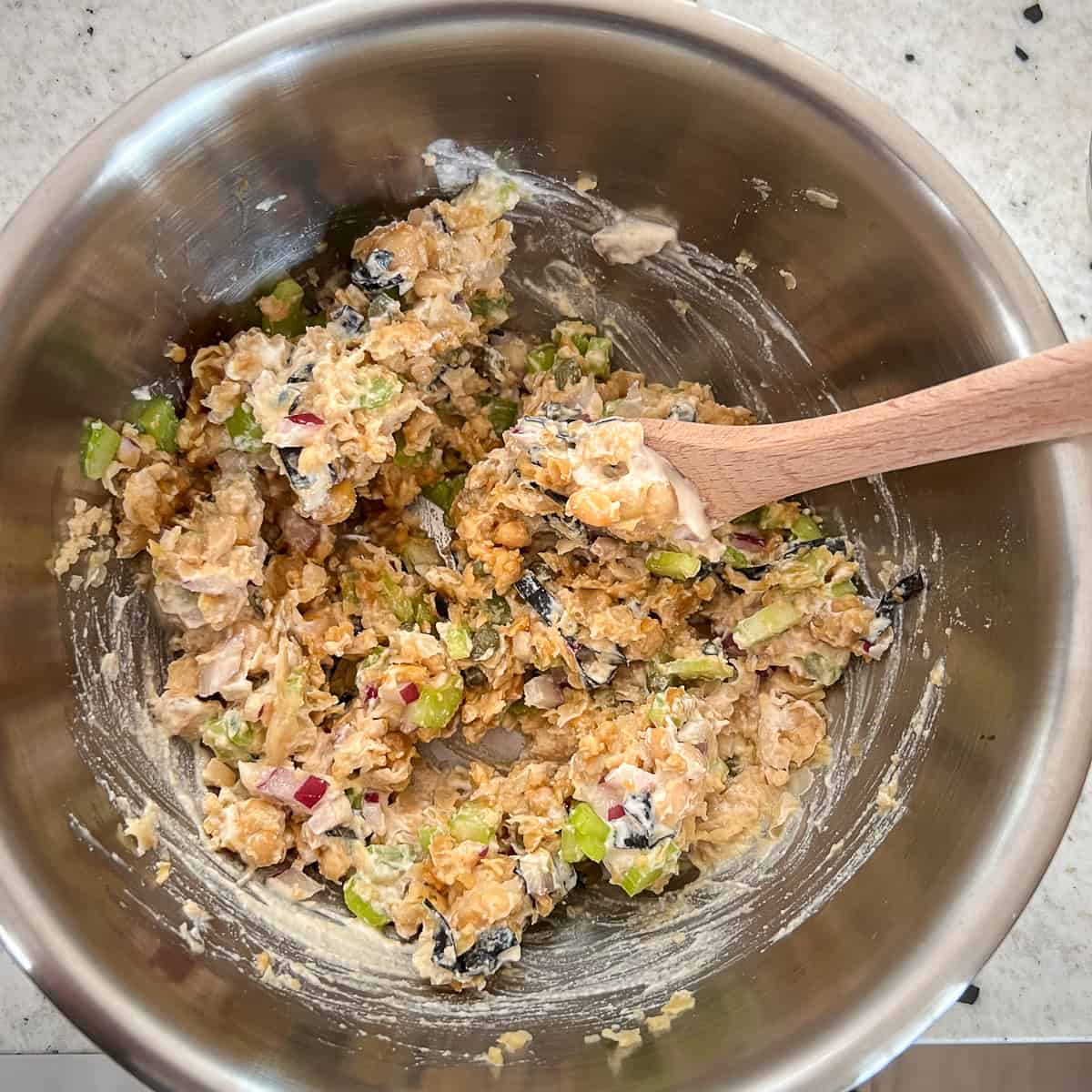 Vegan tuna salad with chickpeas being mixed together in a mixing bowl.