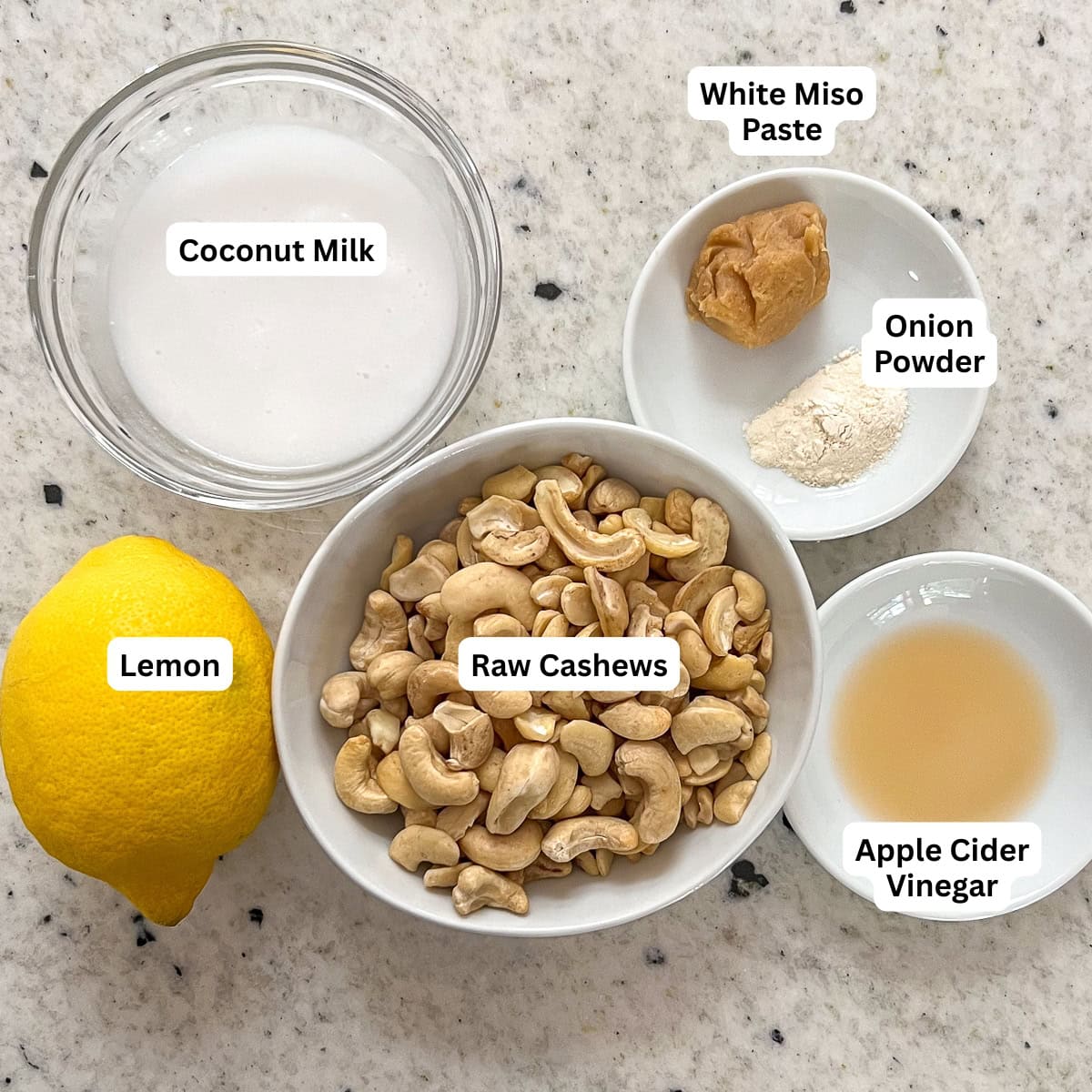 Ingredients for vegan cream cheese: cashews, miso paste, lemon, onion powder, apple cider vinegar, coconut milk.