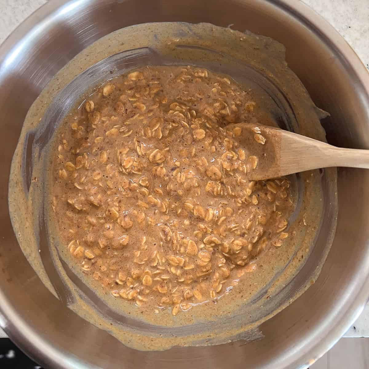 Oatmeal mixture in a bowl with wooden spoon.