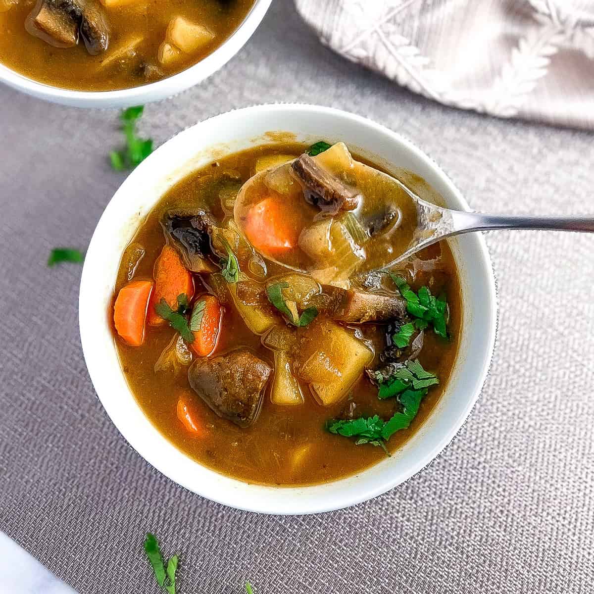 Curry spiced mushroom potato soup in a bowl with spoon; fresh chopped parsley on top.