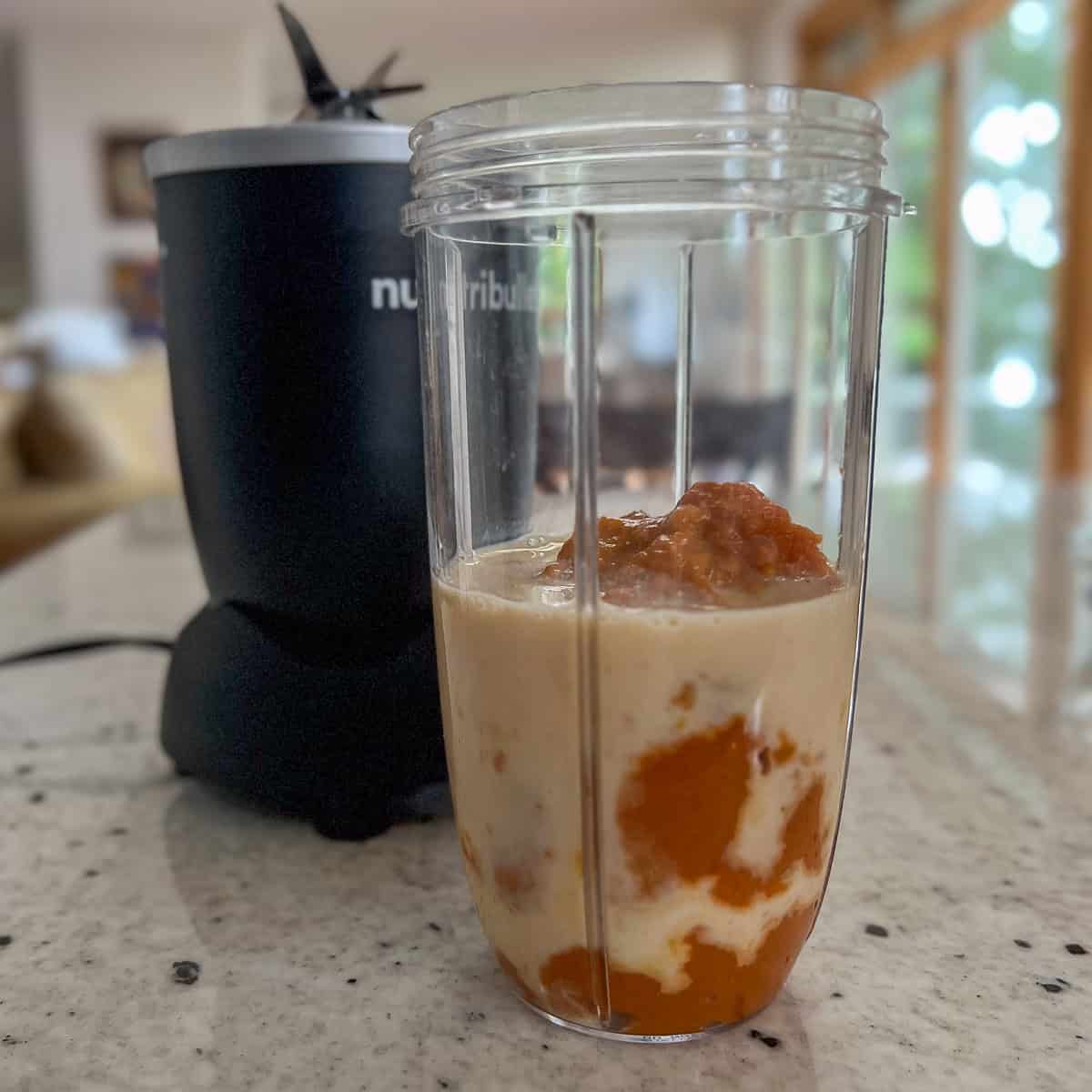 Pumpkin puree and soymilk in a blender cup.