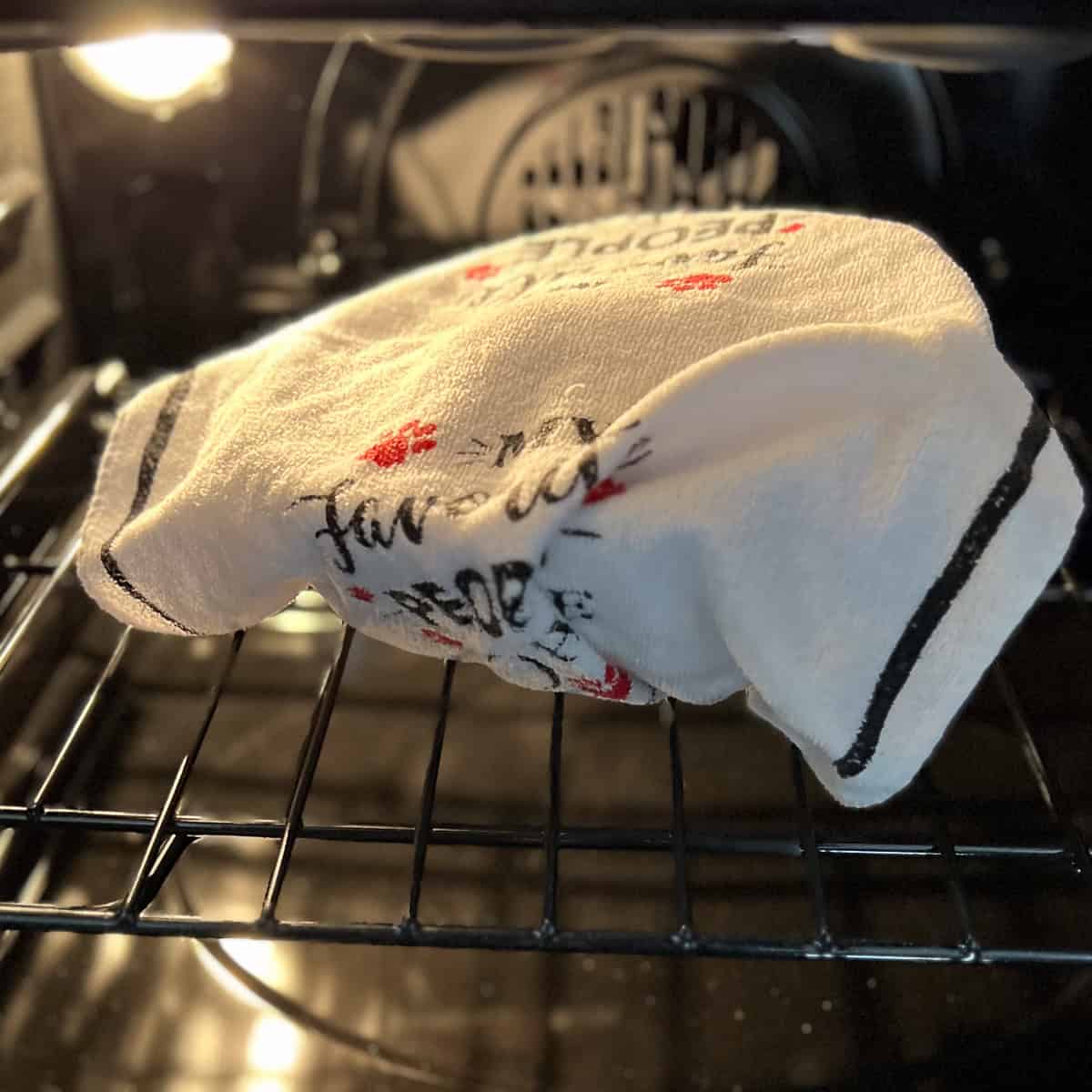 Dough covered in a clean tea towel in the oven with the oven light only on.