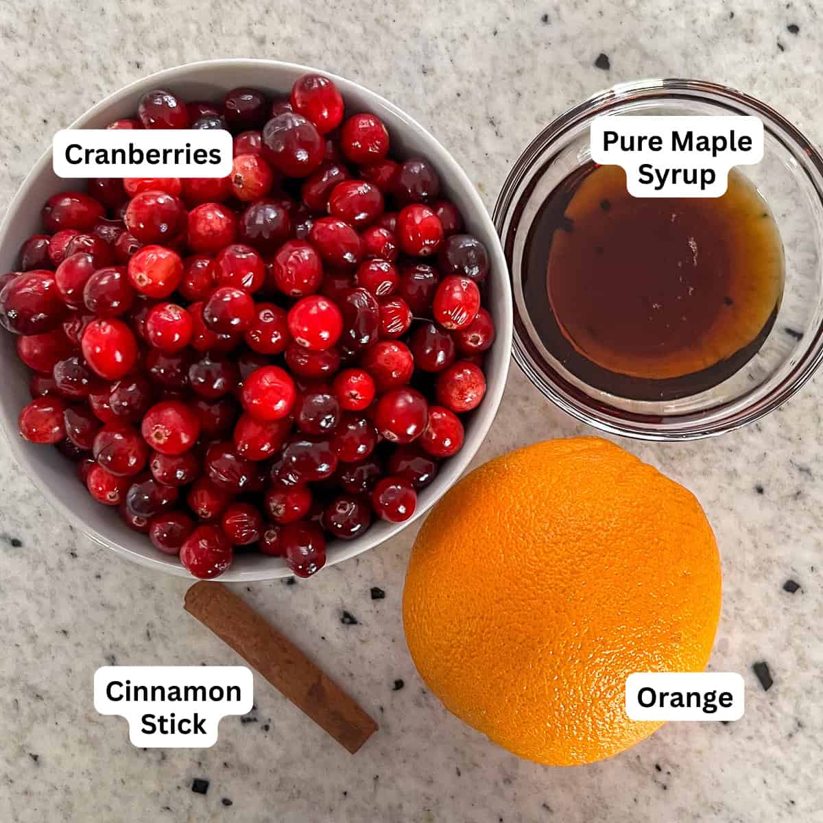 Ingredients for homemade cranberry sauce: fresh cranberries, maple syrup, cinnamon stick and an orange.