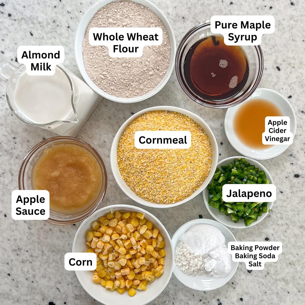 Ingredients for vegan jalapeno cornbread: cornmeal, maple syrup, apple sauce, almond milk, baking powder, baking soda, salt, apple cider vinegar, jalapeno and corn.