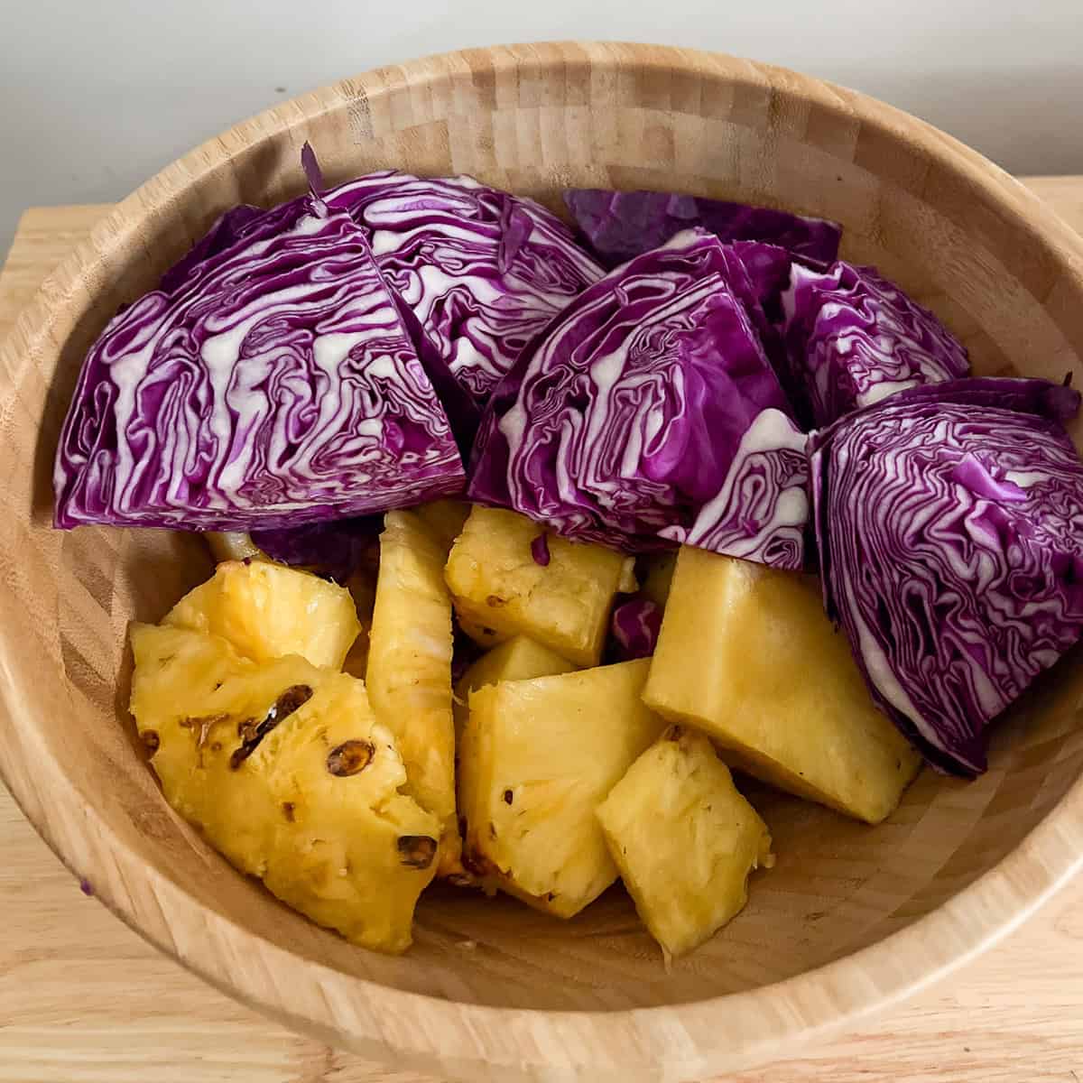 purple cabbage and pineapple chunks in a bowl.