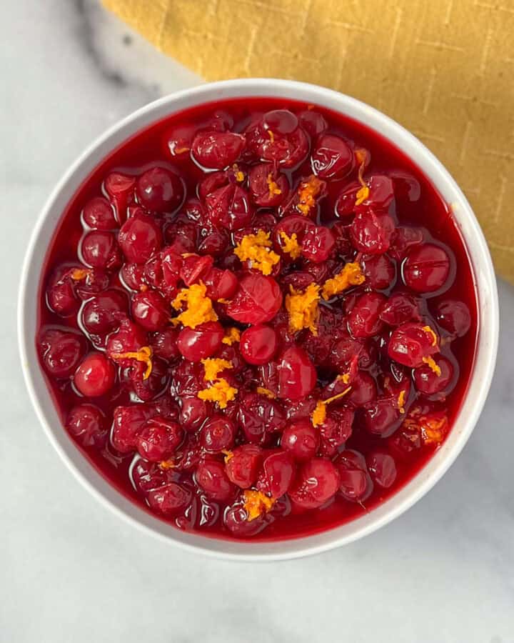 Bowl of homemade cranberry sauce topped with fresh orange zest.