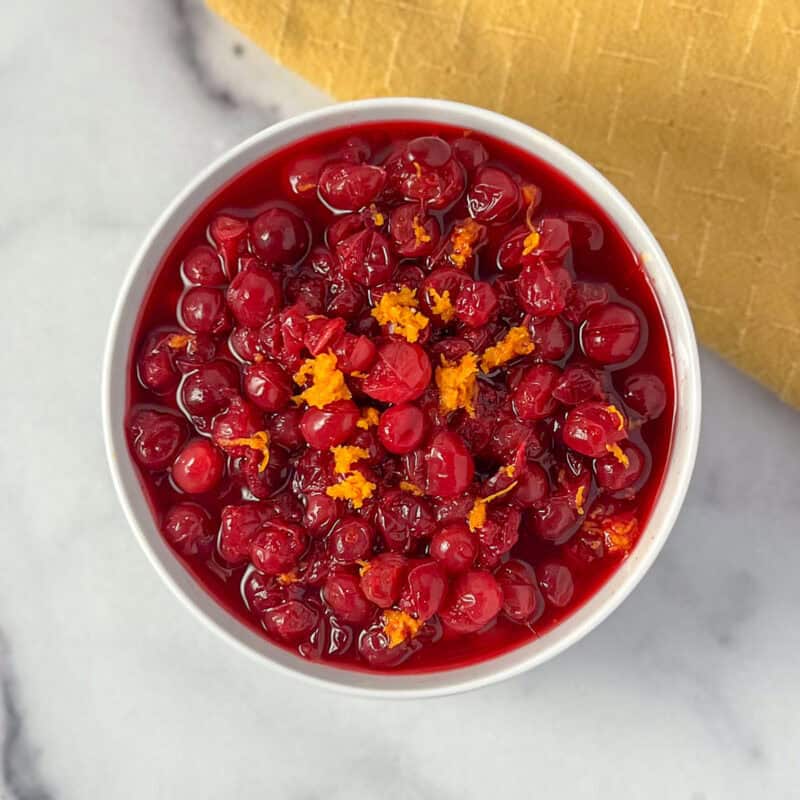 Bowl of homemade cranberry sauce topped with fresh orange zest.