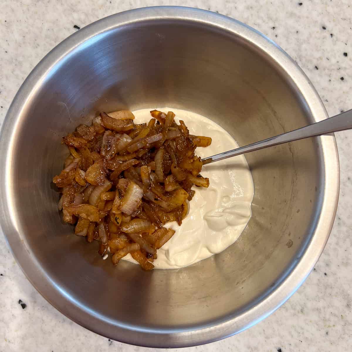 Cashew sour cream and caramelized onion in a mixing bowl.