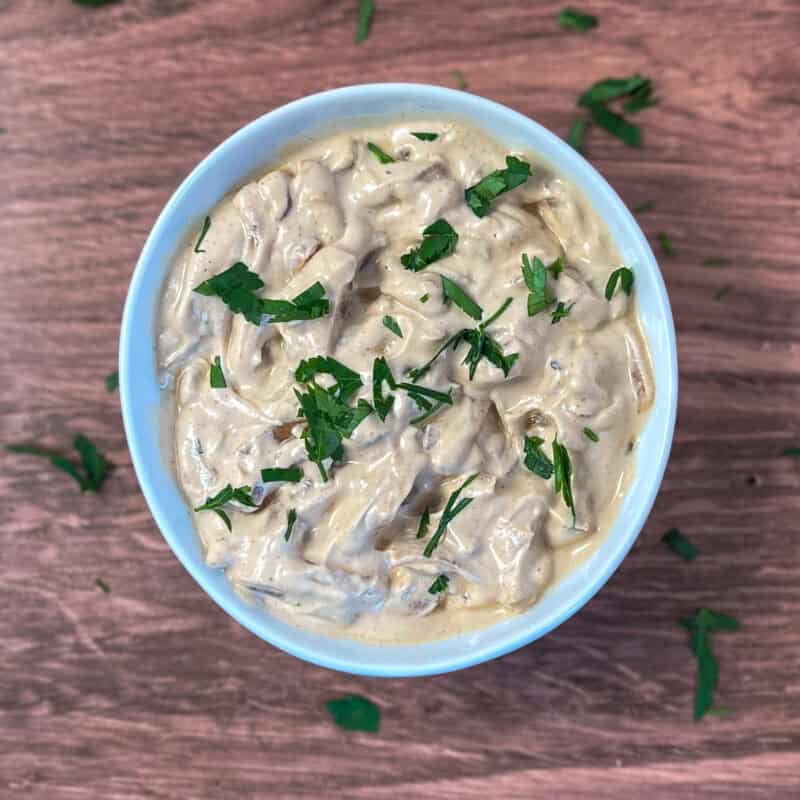 A bowl of French onion dip topped with fresh chopped herbs.