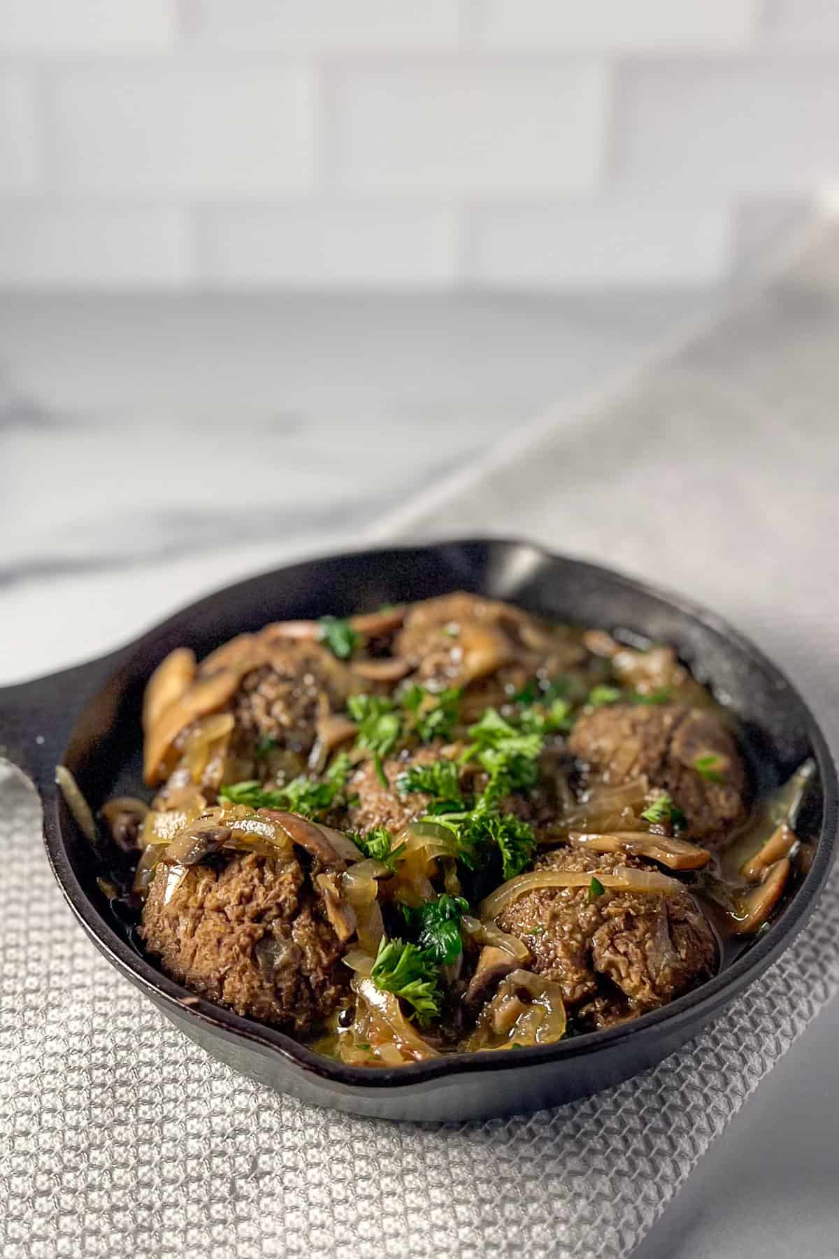 A cast iron skillet with vegan Swedish meatballs and mushroom gravy.