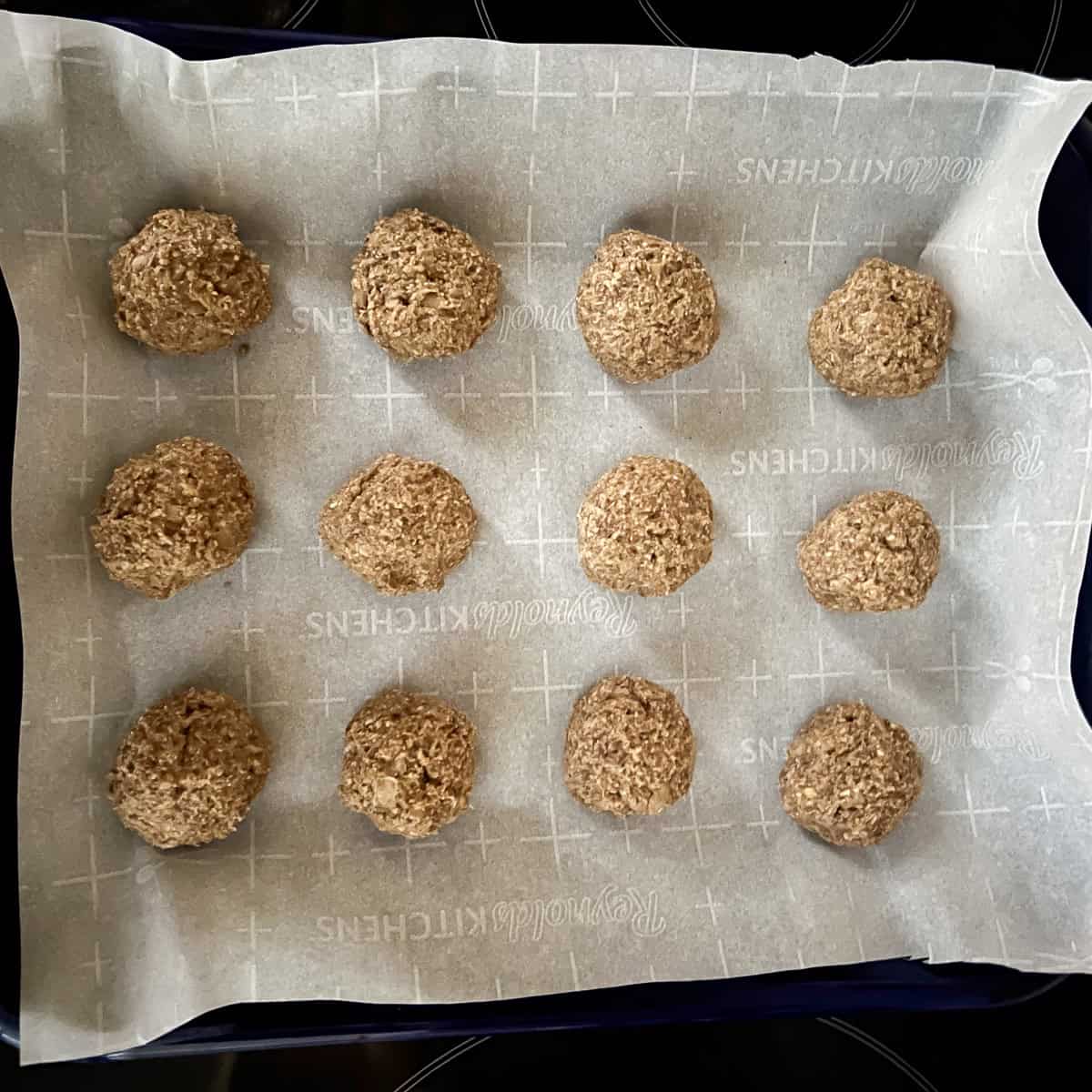 Twelve vegan Swedish meatballs that have been formed and placed on a parchment lined baking sheet.