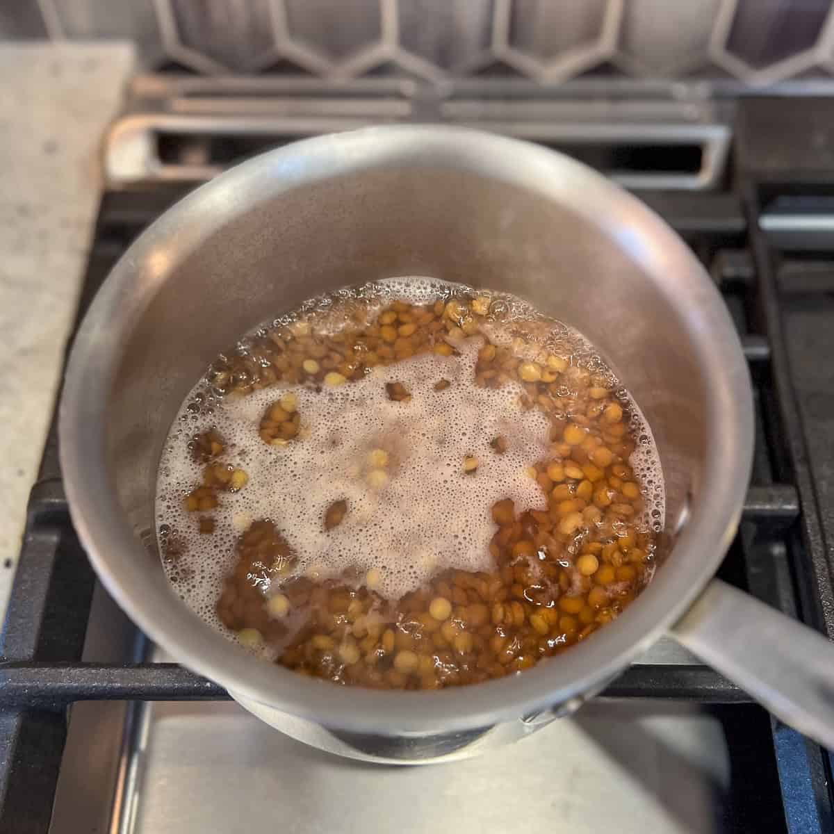 Lentils in a pot on the stovetop simmering.