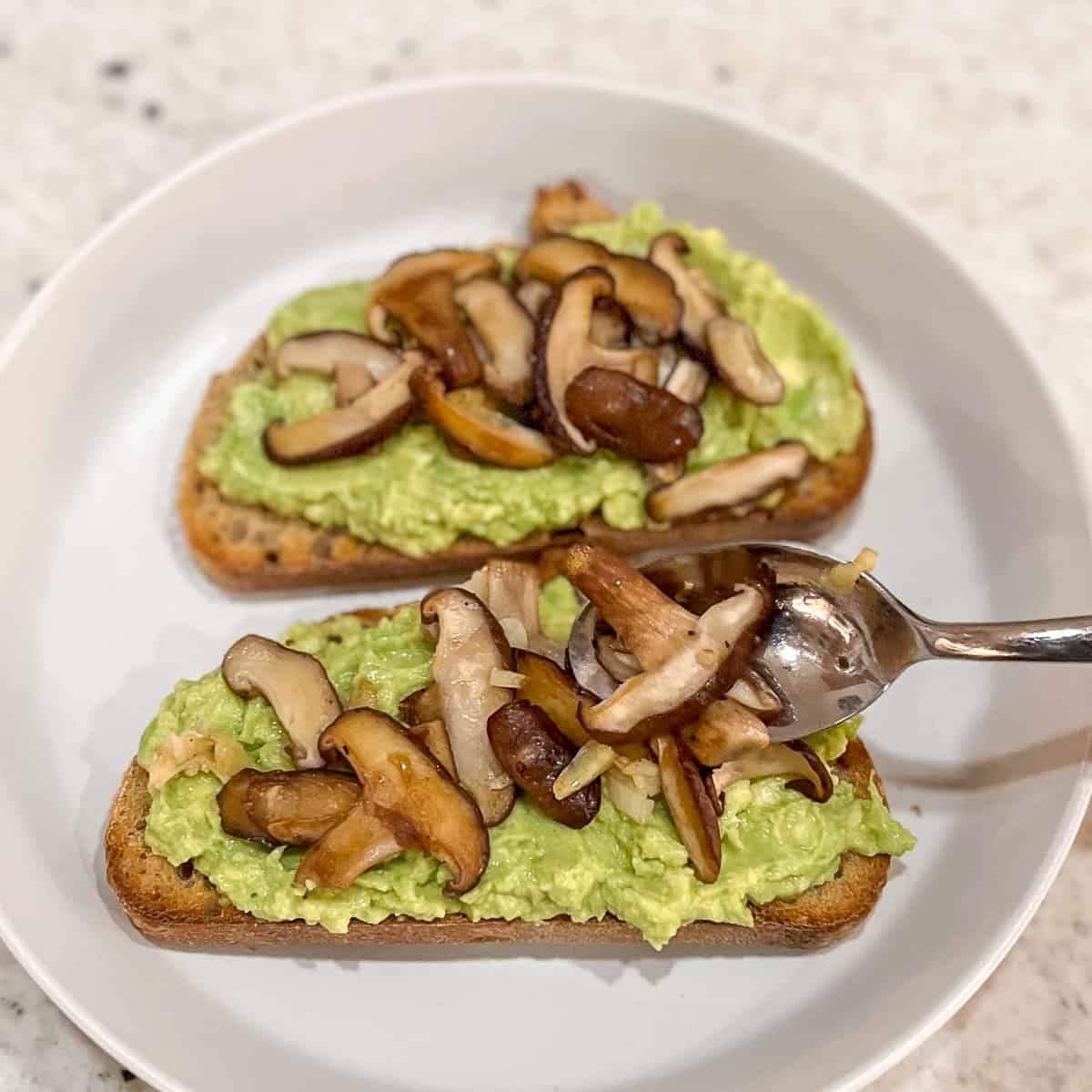 Sautéed mushrooms and garlic being added to the avocado toast.