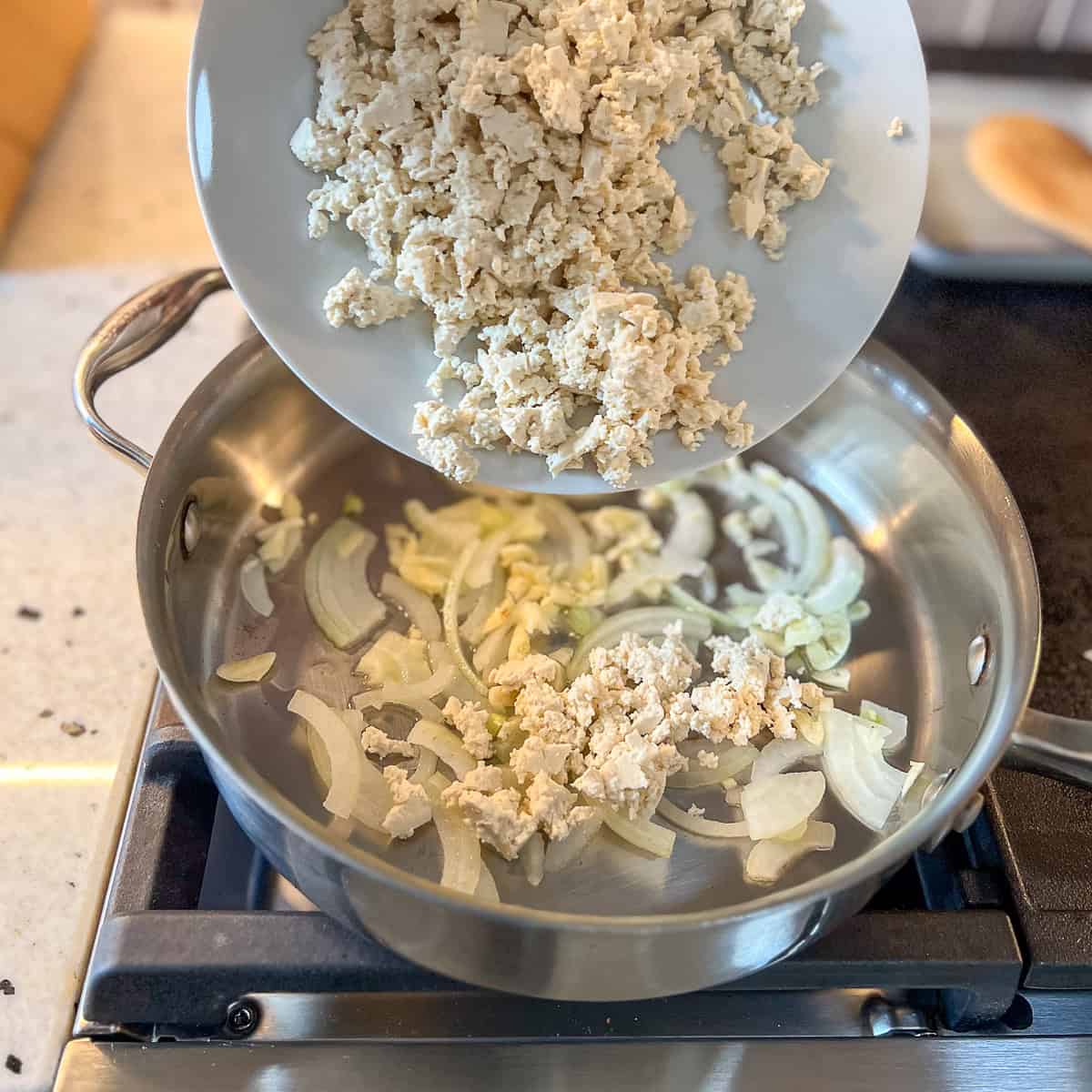 Crumbled tofu that's been added to the skillet with onion and garlic.