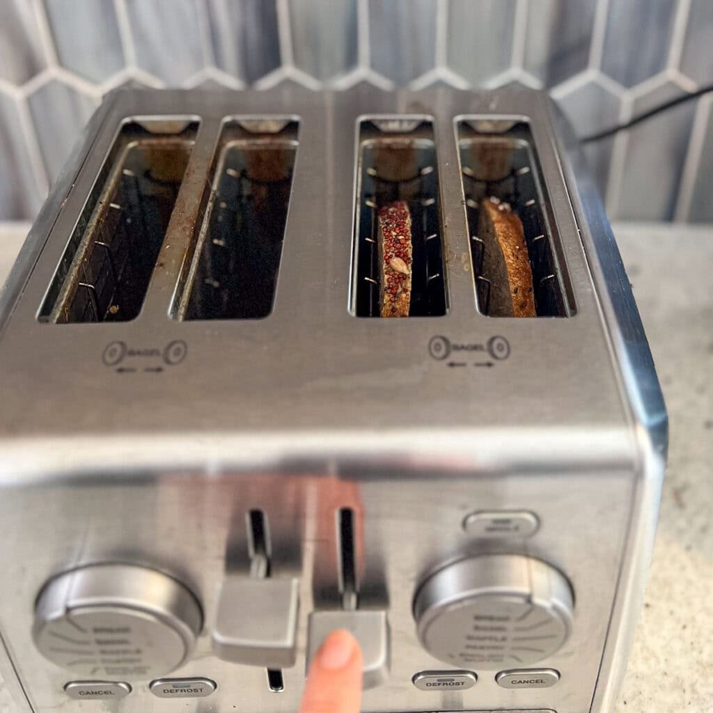 Two slices of bread going into the toaster.
