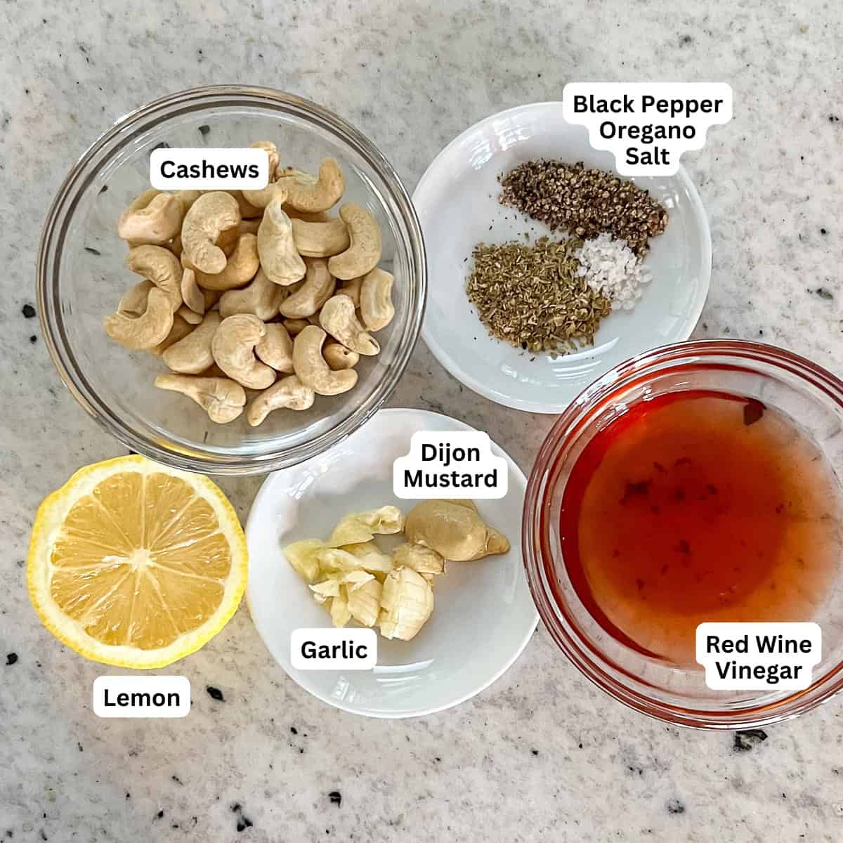 Ingredients for oil free Greek dressing: cashews, vinegar, garlic, Dijon mustard, lemon juice, and seasonings.