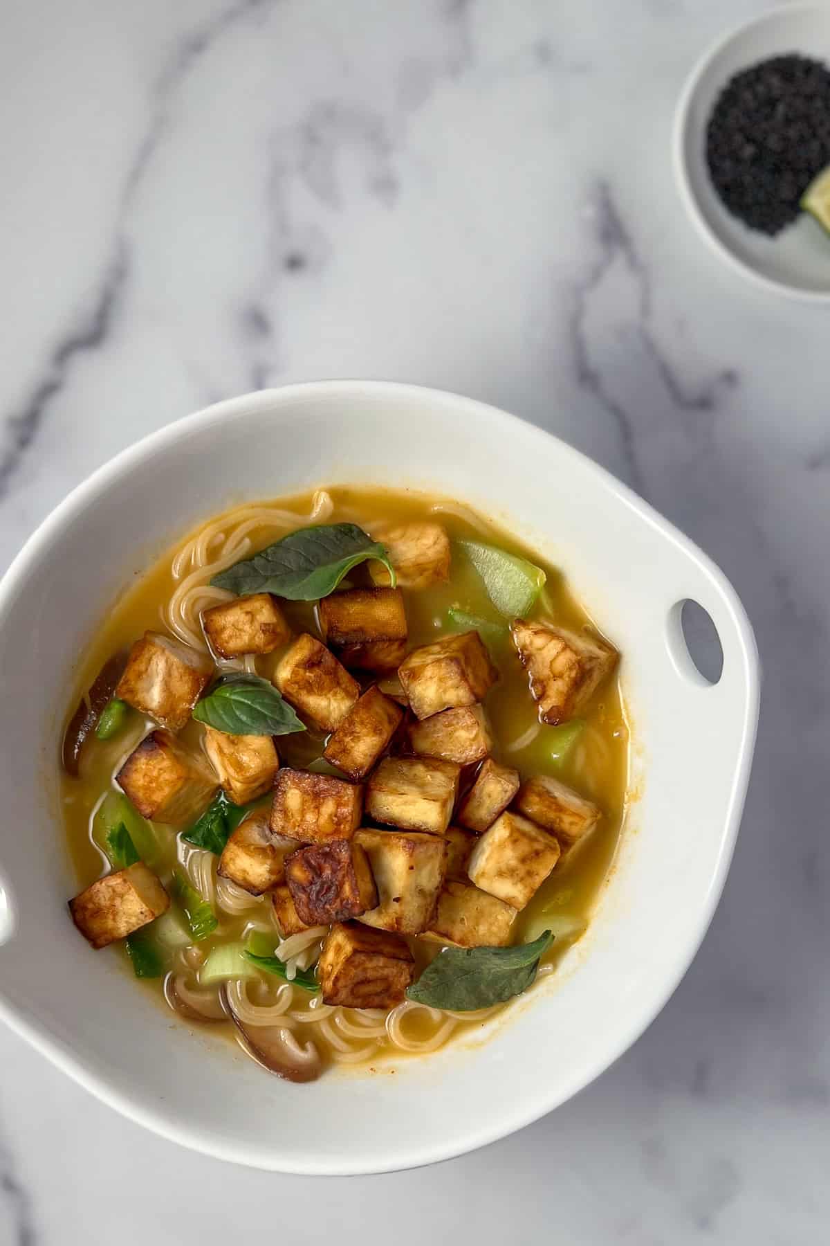 Curry ramen in a bowl with tofu and Thai basil.