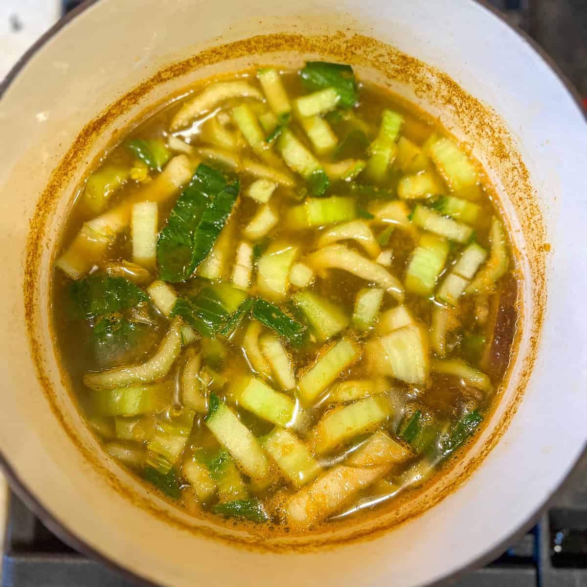 Curry broth with veggies in a pot.