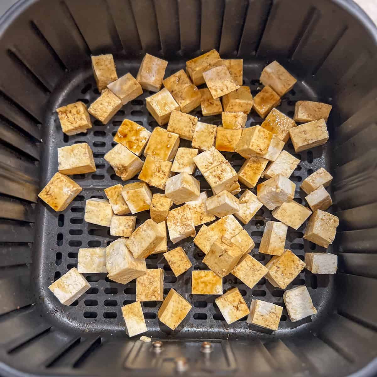 Tofu chunks in the air fryer basket.