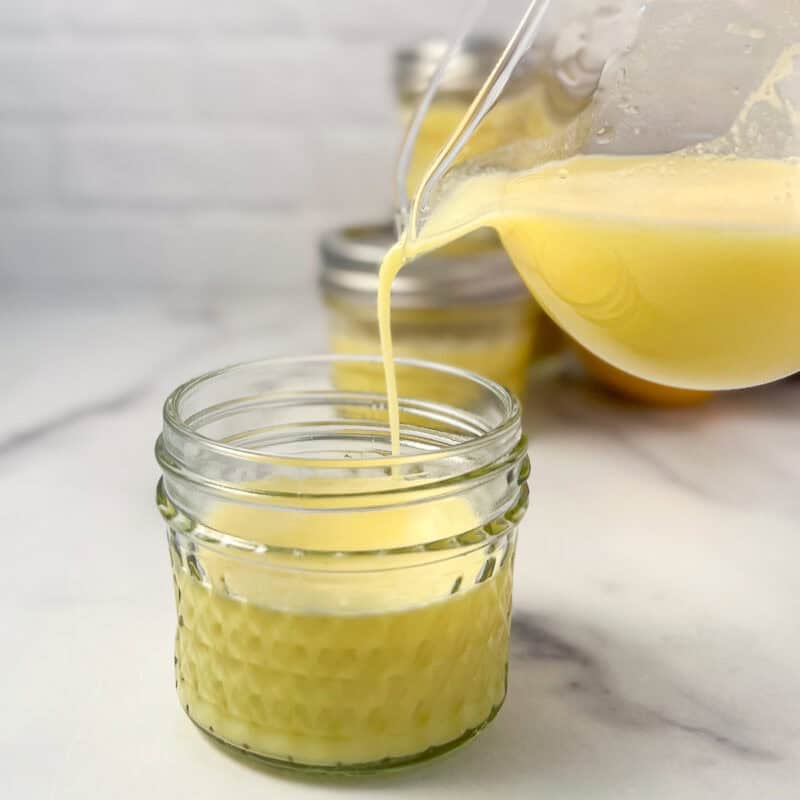 Lemon and ginger juice being poured into small mason jars.