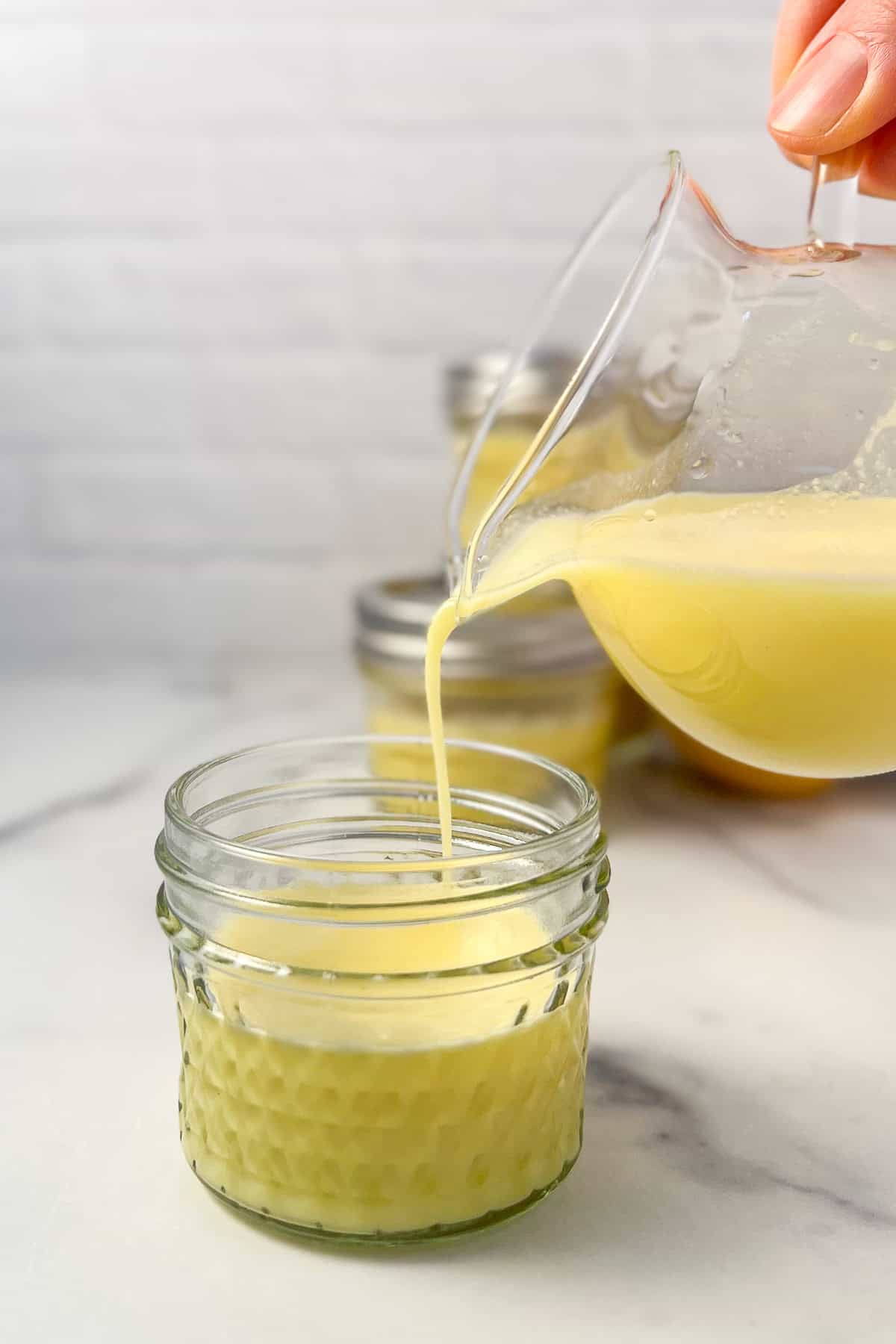 Lemon and ginger juice being poured into a small mason jar.