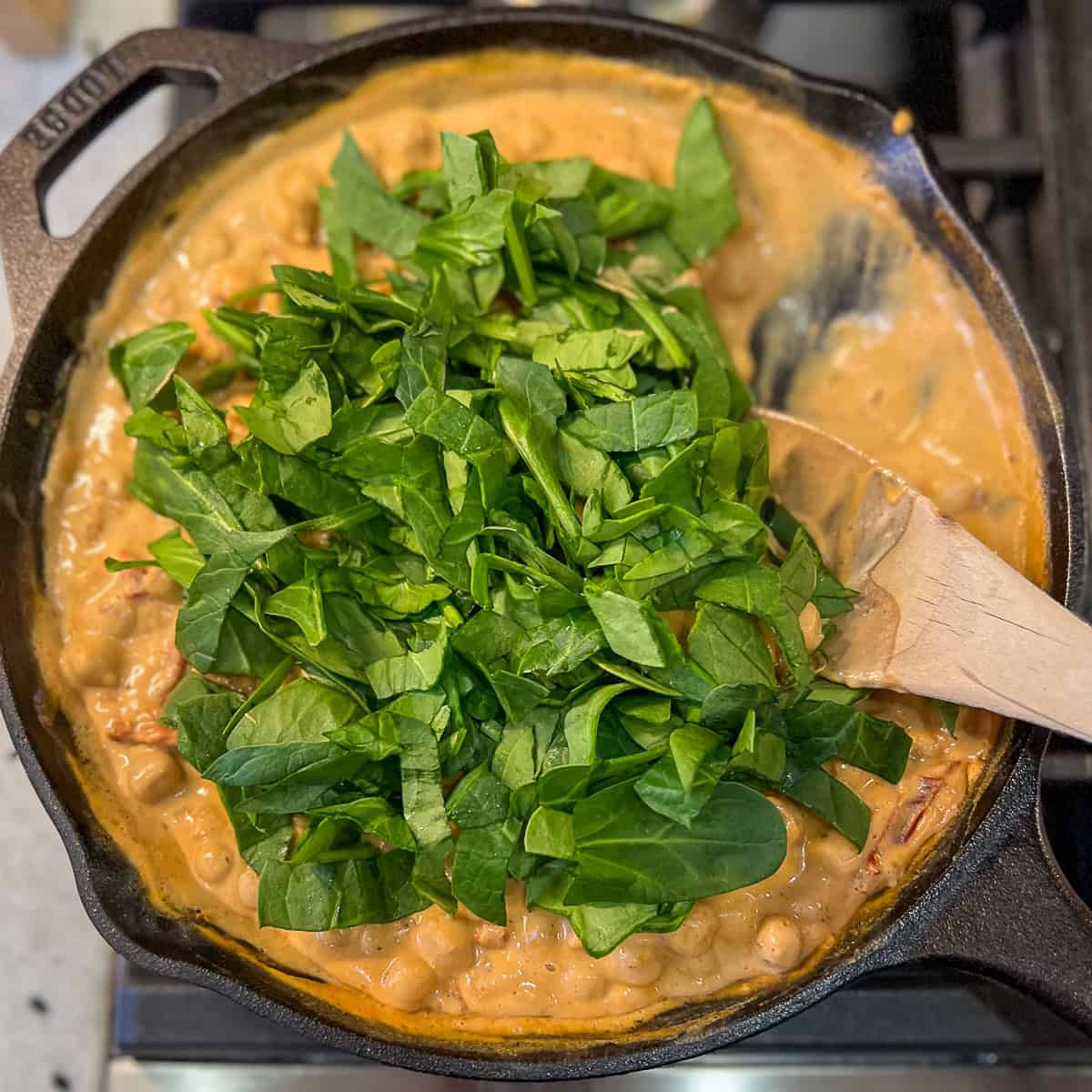 Chopped spinach added to the skillet with Marry Me Chickpeas.