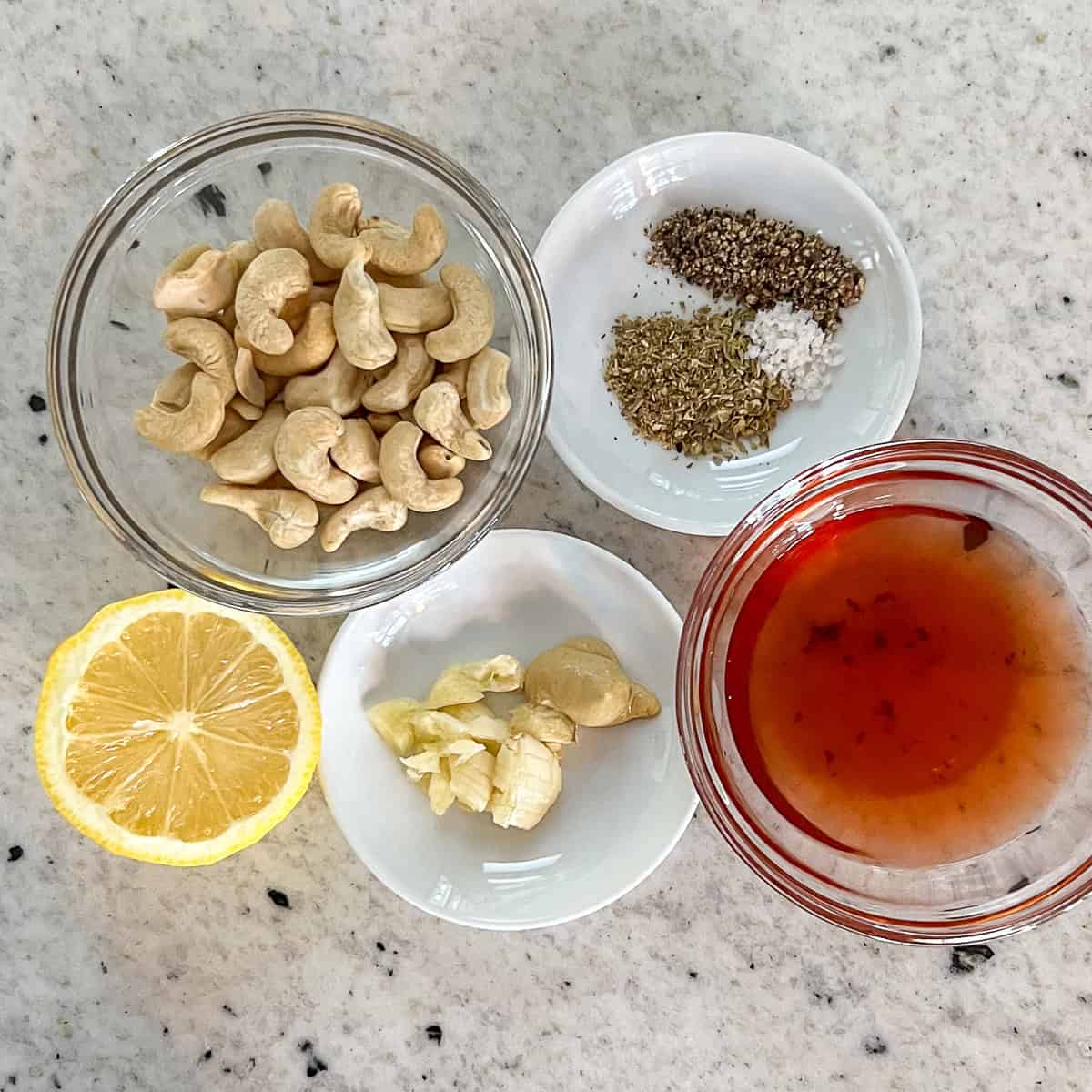 Ingredients for oil free Greek dressing: cashews, vinegar, garlic, Dijon mustard, lemon juice, and seasonings.