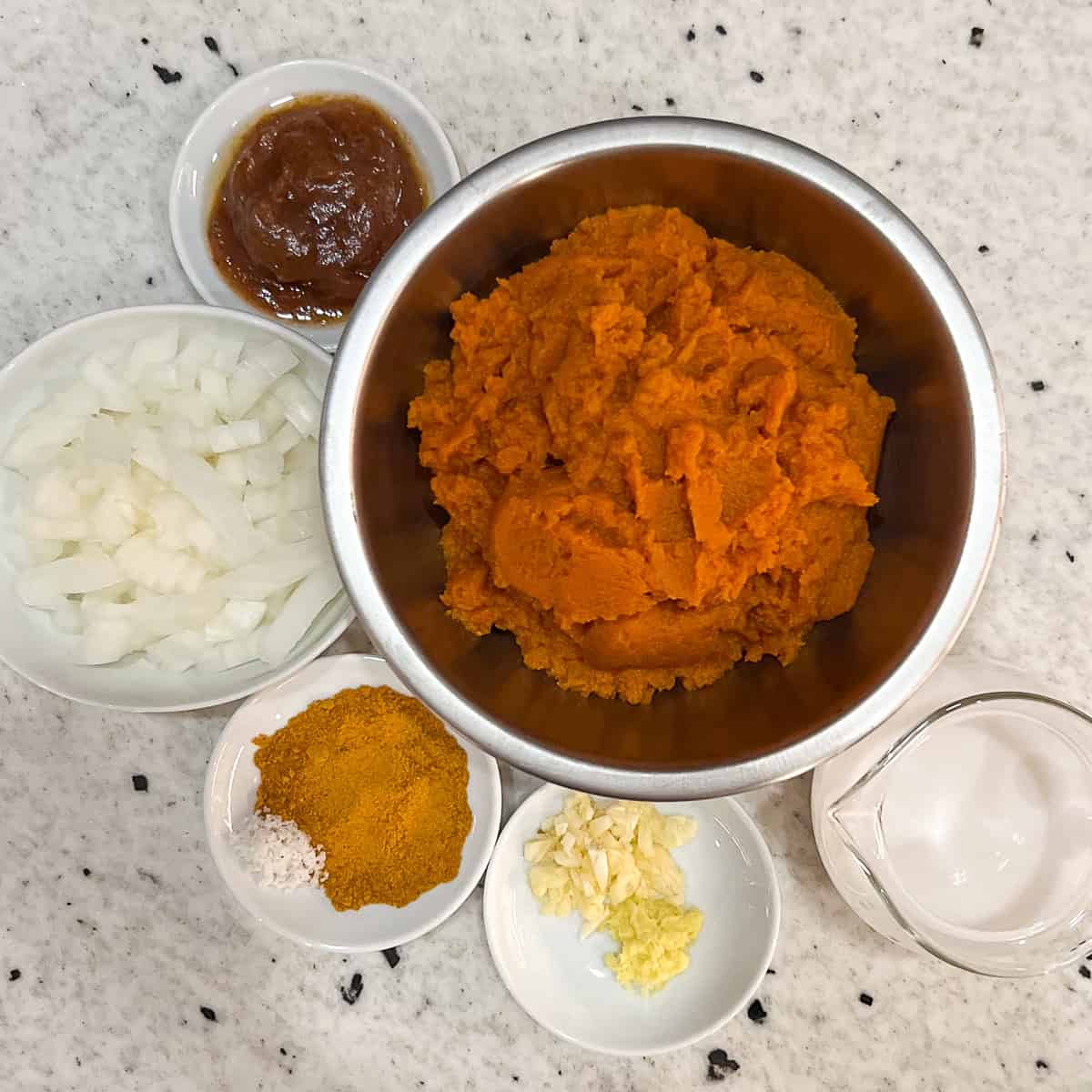 Ingredients for pumpkin curry soup: pumpkin puree, onion, garlic, ginger root, homemade date syrup, curry powder, plain unsweetened coconut milk.