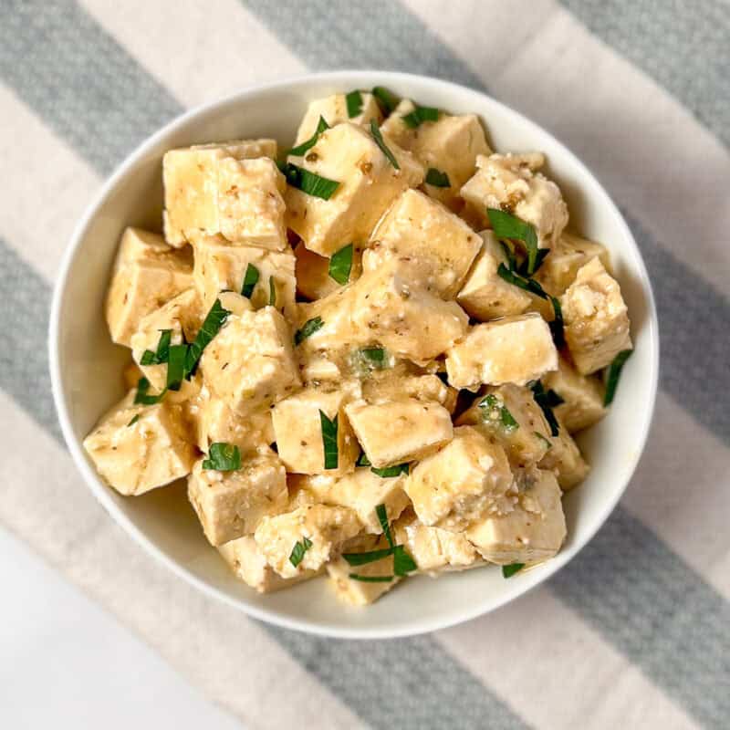 Vegan feta in a bowl with chopped parsley.